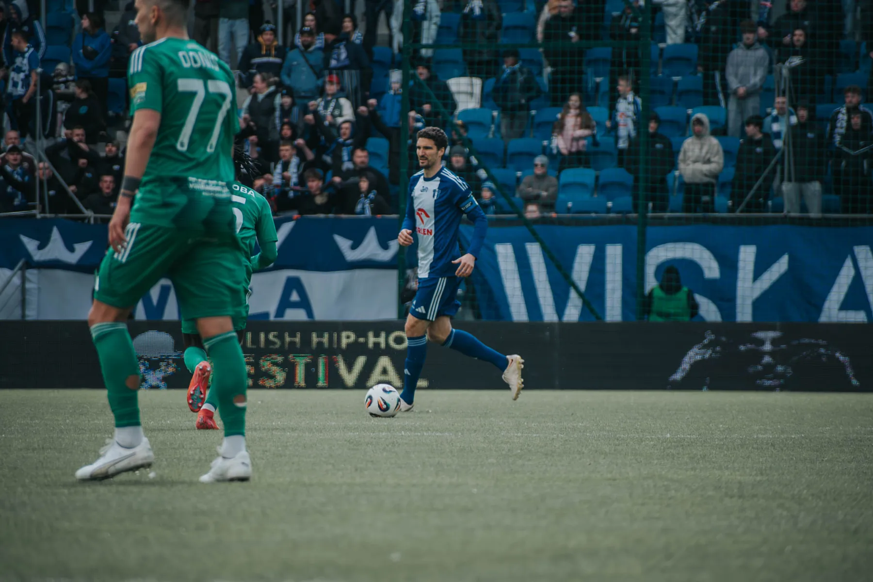 Piłkarz prowadzi piłkę na stadionie podczas meczu.